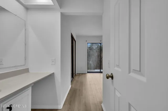 a view of a hallway with wooden floor and a bathroom