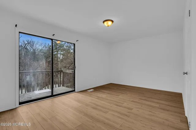 a view of an empty room with wooden floor and fan