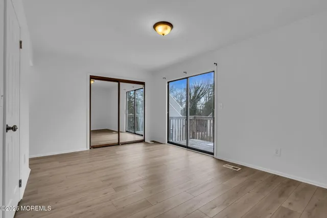 a view of an empty room with wooden floor and window