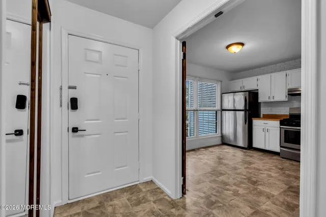 a view of kitchen with refrigerator and white cabinets
