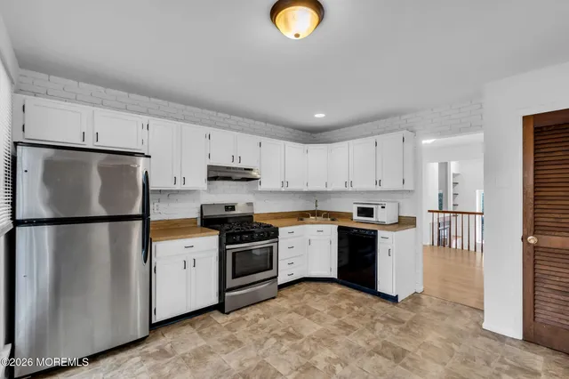 a kitchen with stainless steel appliances granite countertop a refrigerator a stove a sink and a microwave