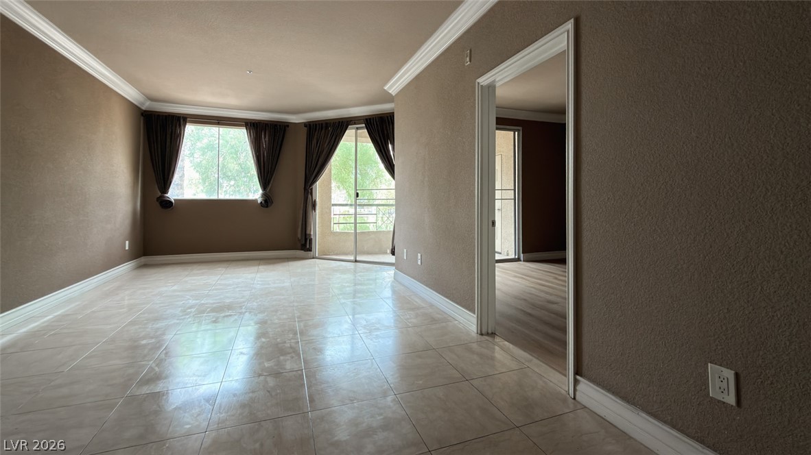 210 East Flamingo Road, Unit 112 Las Vegas, NV 89169 - Photo 2 of 59 Tiled flooring and crown molding define this open living area with outdoor balcony access.