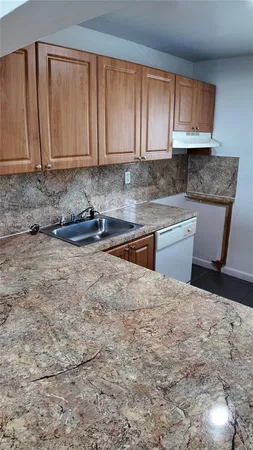 a kitchen with granite countertop a sink a stove and cabinets