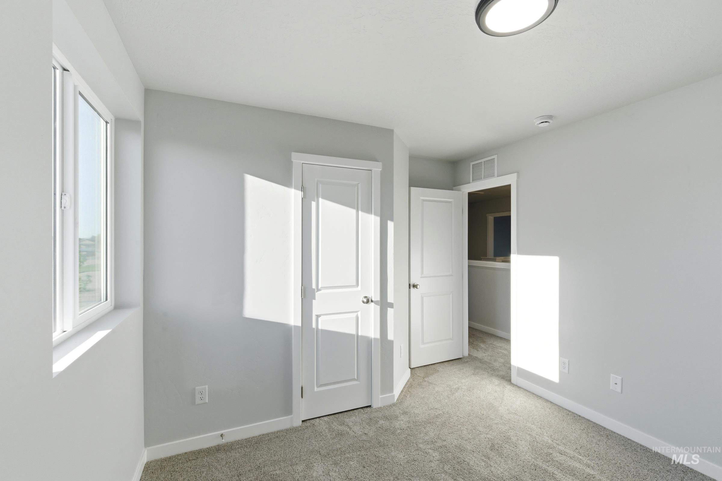 13709 Redway Court Caldwell, ID 83607 - Photo 17 of 28 Carpeted room with a white window frame, white interior doors, and a round ceiling light fixture