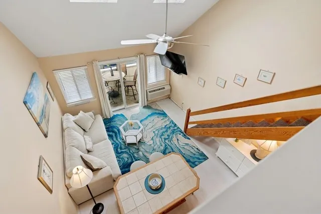 a living room with stainless steel appliances furniture a rug and a kitchen view
