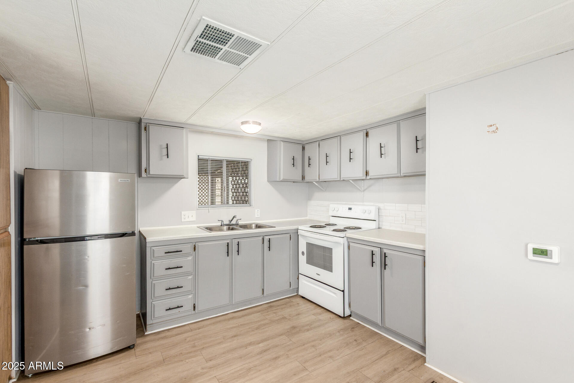16225 North Cave Creek Road, Unit 140 Phoenix, AZ 85032 - Photo 12 of 32 a kitchen with stainless steel appliances granite countertop a refrigerator a stove a sink and white cabinets