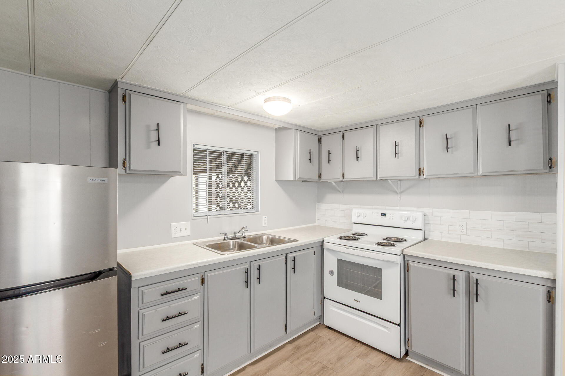 16225 North Cave Creek Road, Unit 140 Phoenix, AZ 85032 - Photo 14 of 32 a kitchen with cabinets appliances a sink and a window