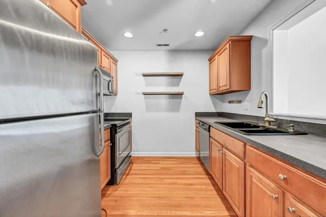 a kitchen with stainless steel appliances granite countertop a refrigerator a sink and a stove