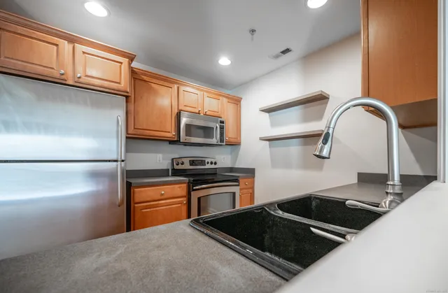 a kitchen with stainless steel appliances granite countertop a stove a sink dishwasher and a refrigerator