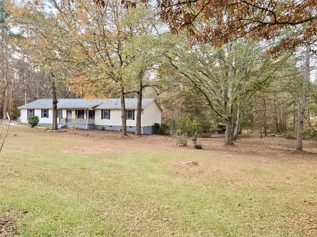 a view of house with yard and trees in the background