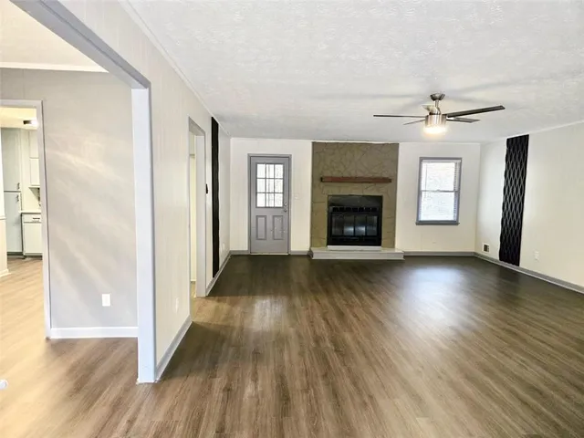 an empty room with wooden floor fireplace and windows