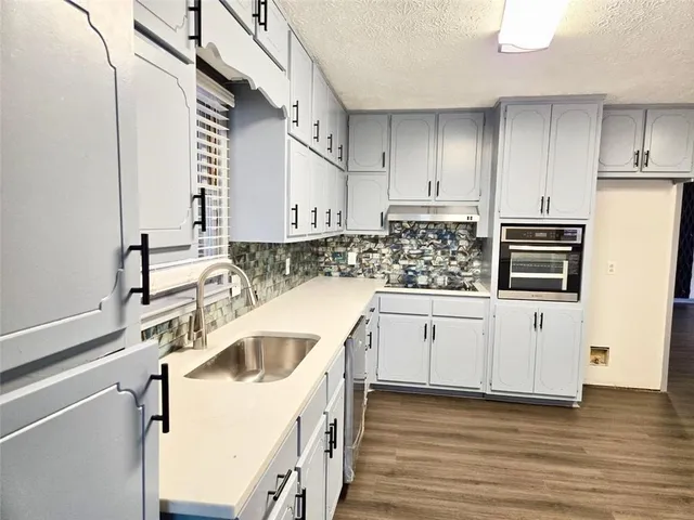 a kitchen with granite countertop a sink a stove and cabinets