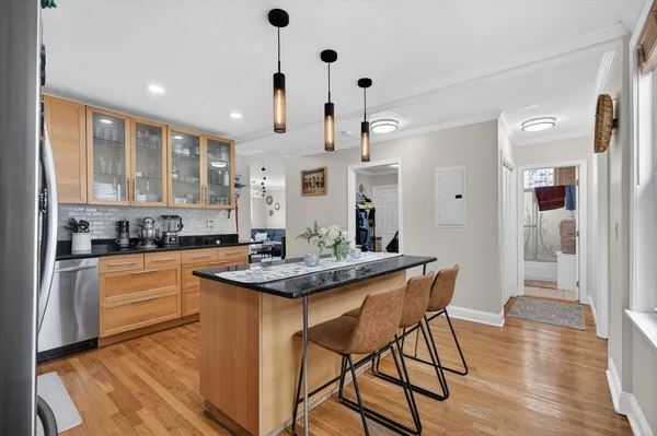 a kitchen with stainless steel appliances granite countertop a stove a sink a microwave a refrigerator and white cabinets with wooden floor