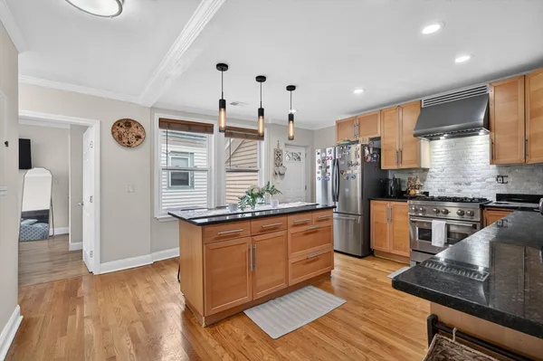 a large kitchen with stainless steel appliances granite countertop a stove a sink dishwasher and a refrigerator with wooden floor