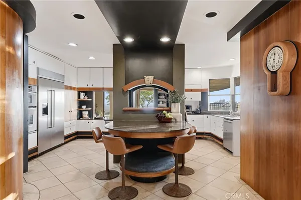a living room with furniture a clock and a view of kitchen