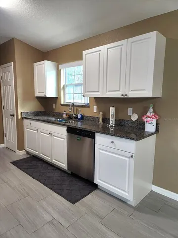 a kitchen with granite countertop a sink cabinets and stainless steel appliances