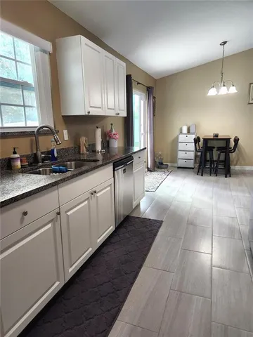 a kitchen with stainless steel appliances granite countertop a stove a sink and a granite counter tops with white cabinets