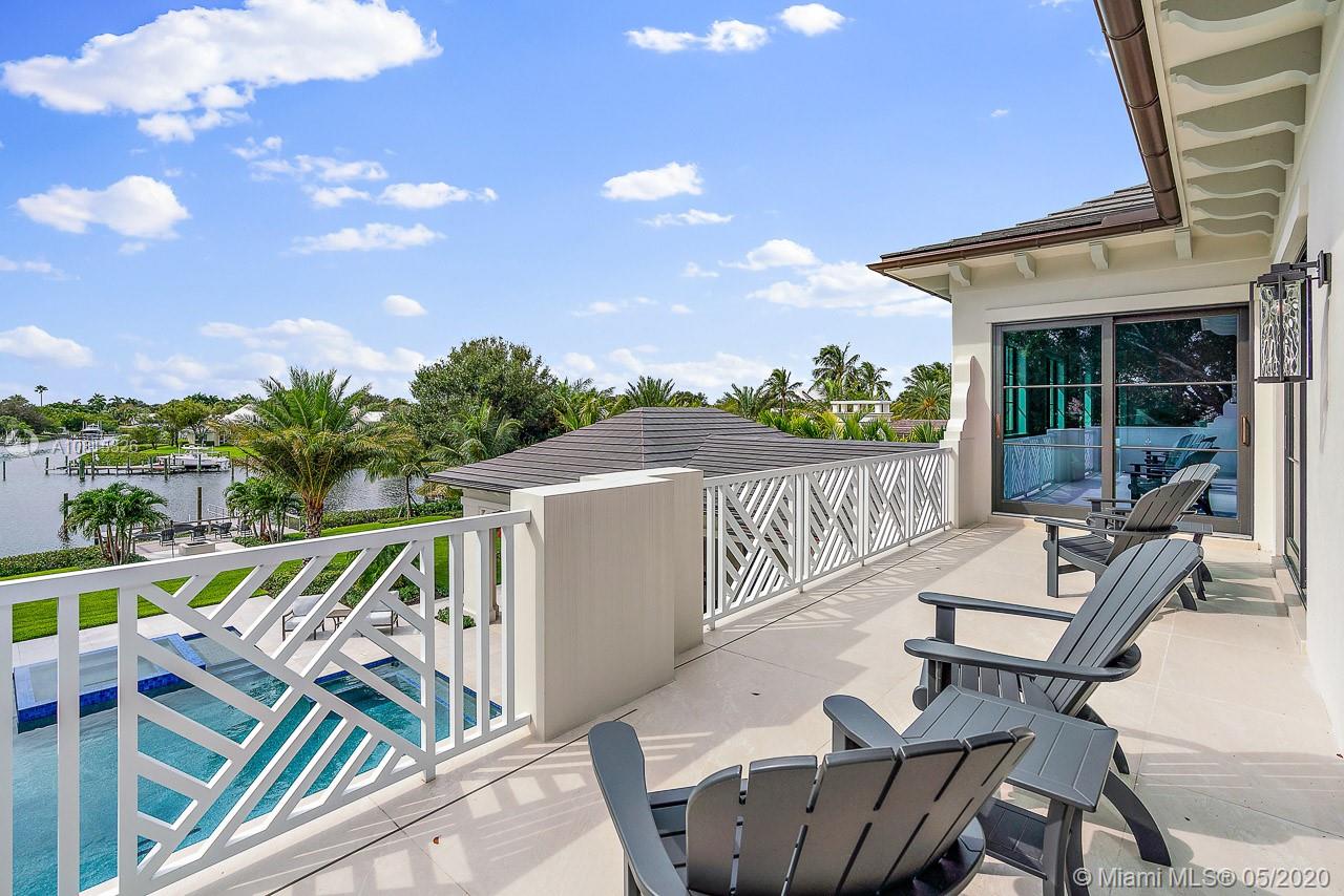 220 Commodore Drive Jupiter, FL 33477 - Photo 40 of 55 a view of a patio with a table and chairs under an umbrella with wooden floor and fence