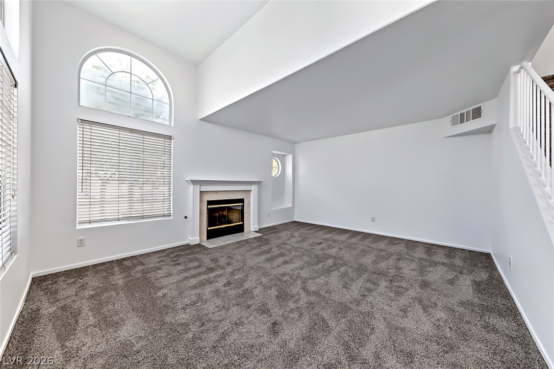205 Genesee Point Street Henderson, NV 89074 - Photo 6 of 30 An arched window and a classic fireplace accent this soaring living area with plush carpeting.