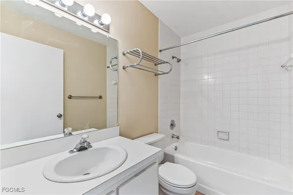 a bathroom with a bathtub shower sink vanity mirror and toilet