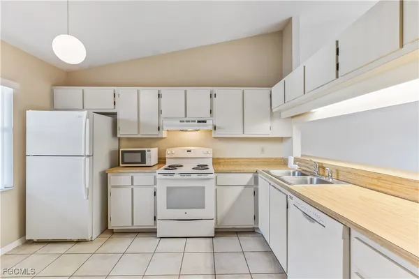 a kitchen with a sink a stove a refrigerator and white cabinets