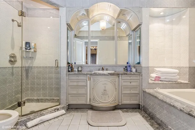 a bathroom with a granite countertop sink mirror vanity bathtub and toilet