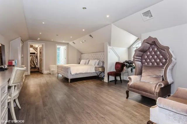 a spacious bedroom with a bed a couch and a potted plant on the dresser