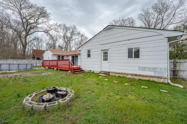 a backyard of a house with wooden table and chairs