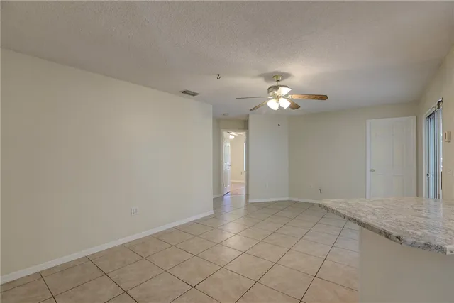 a view of an empty room and chandelier fan