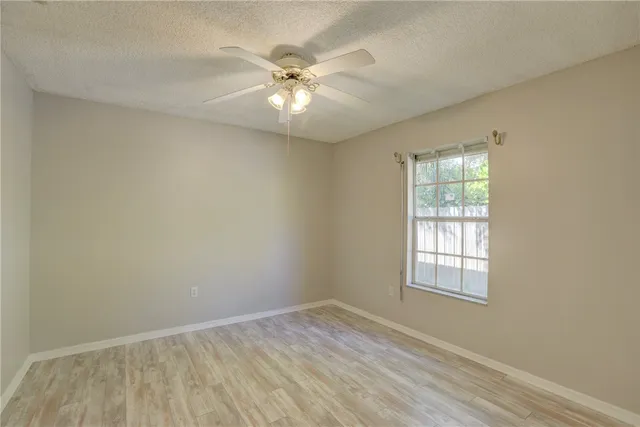 an empty room with windows and fan