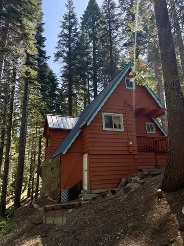 a view of a small house with yard and covered with trees
