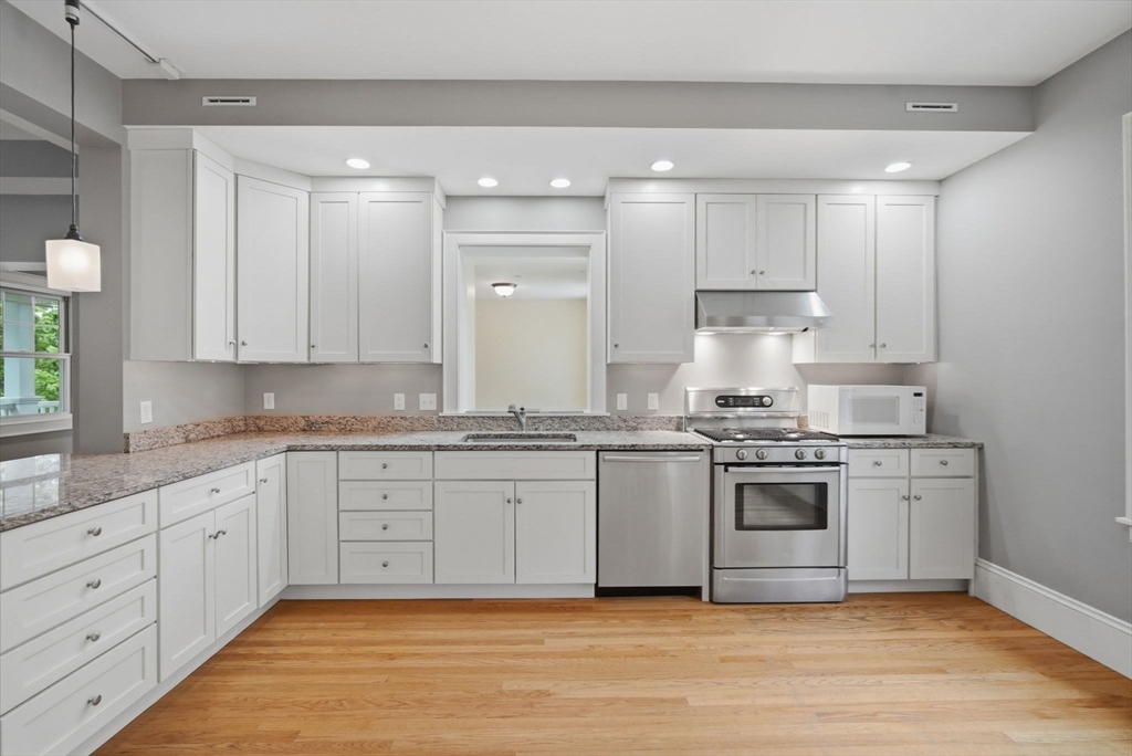 151 Amity Street, Unit 2 Amherst, MA 01002 - Photo 18 of 42 a large kitchen with granite countertop a stove top oven a sink and white cabinets