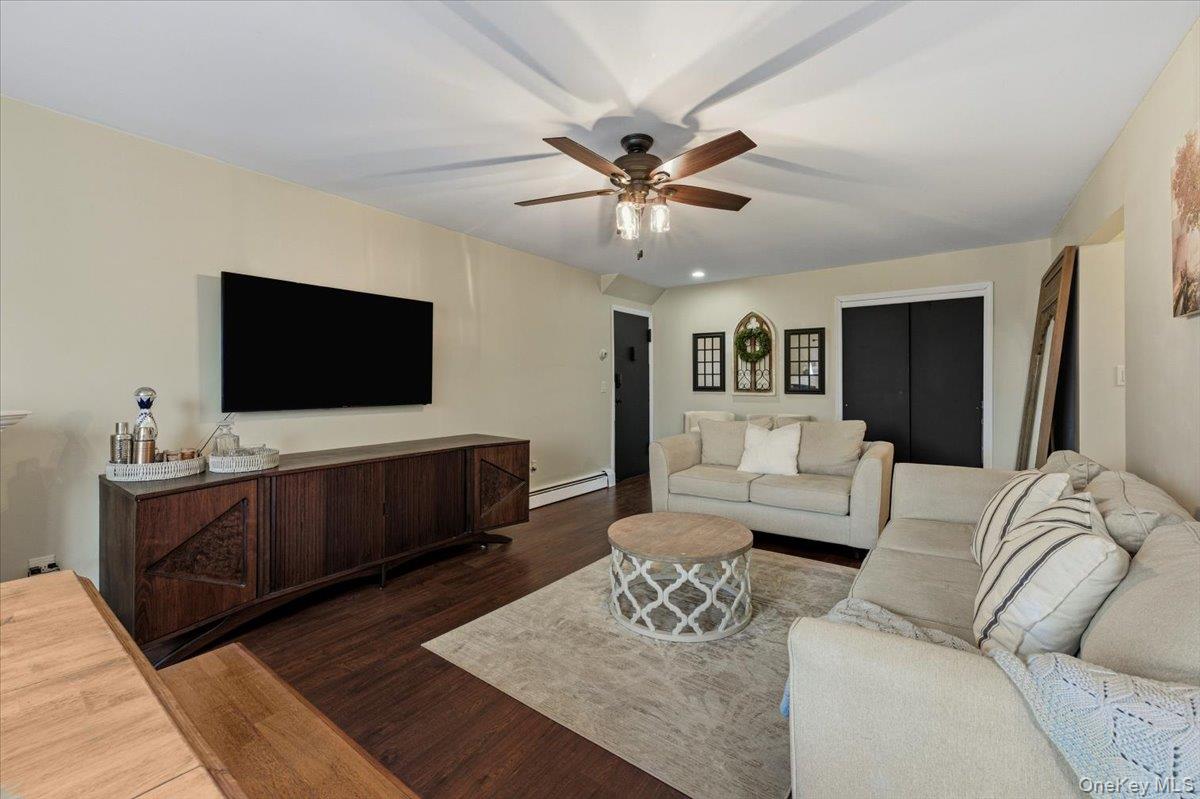 Living area with a baseboard radiator, wood finished floors, and ceiling fan