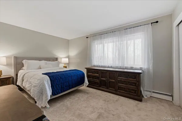 a bedroom with a bed and a computer on a desk next to a window