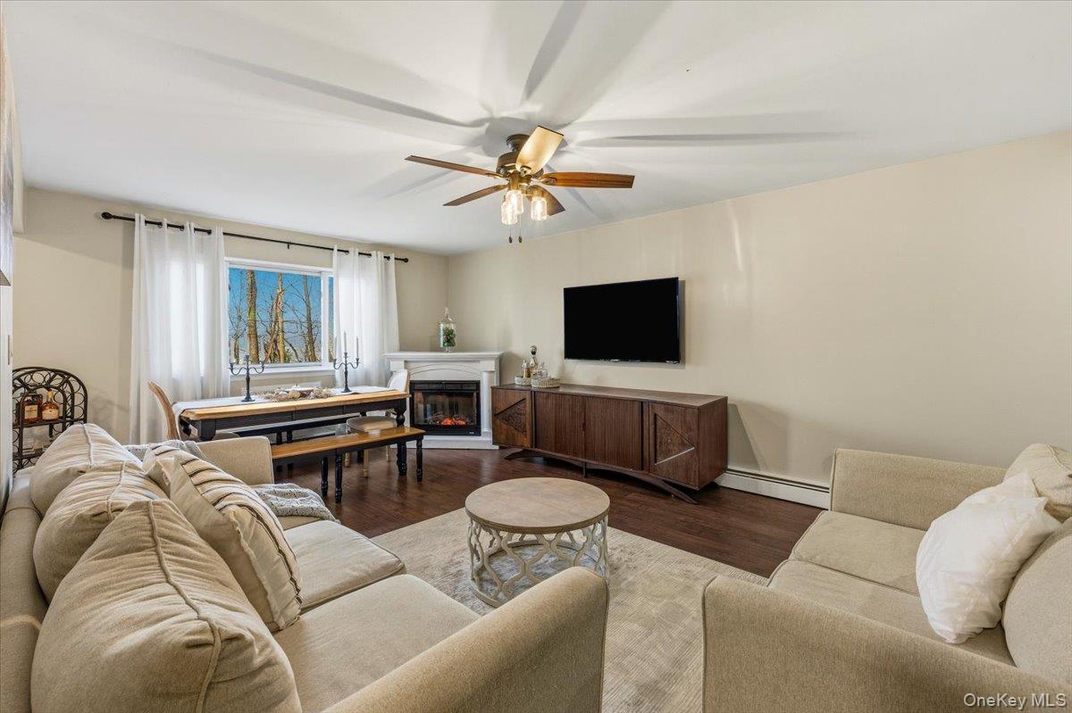9 North James Street, Unit B Peekskill, NY 10566 - Photo 3 of 22 Living area with wood finished floors, fireplace, a baseboard heating unit, and ceiling fan