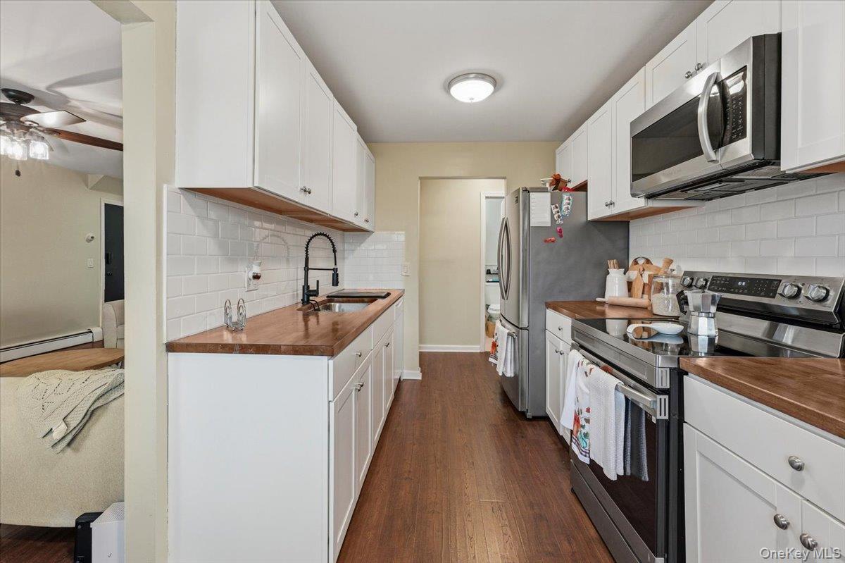 9 North James Street, Unit B Peekskill, NY 10566 - Photo 5 of 22 Kitchen featuring stainless steel appliances, dark wood-style flooring, white cabinets, butcher block counters, and ceiling fan