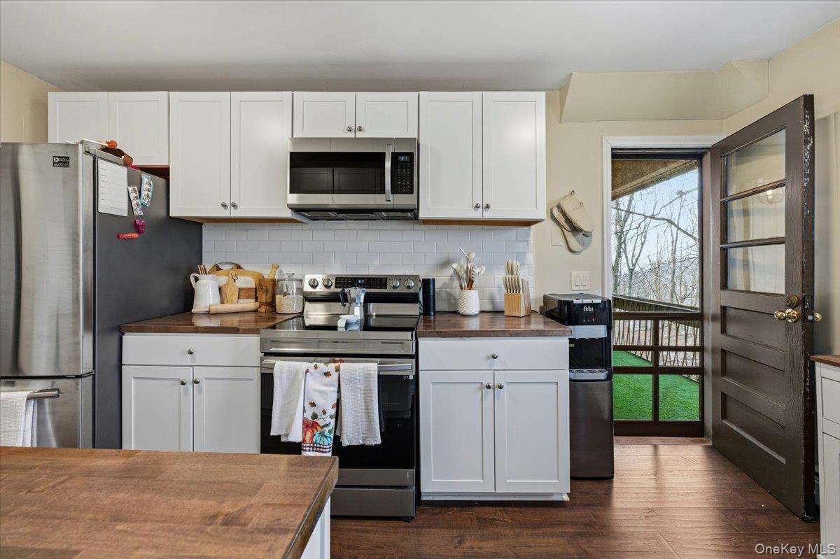 9 North James Street, Unit B Peekskill, NY 10566 - Photo 7 of 22 Kitchen with appliances with stainless steel finishes, white cabinets, dark wood-style floors, backsplash, and butcher block counters