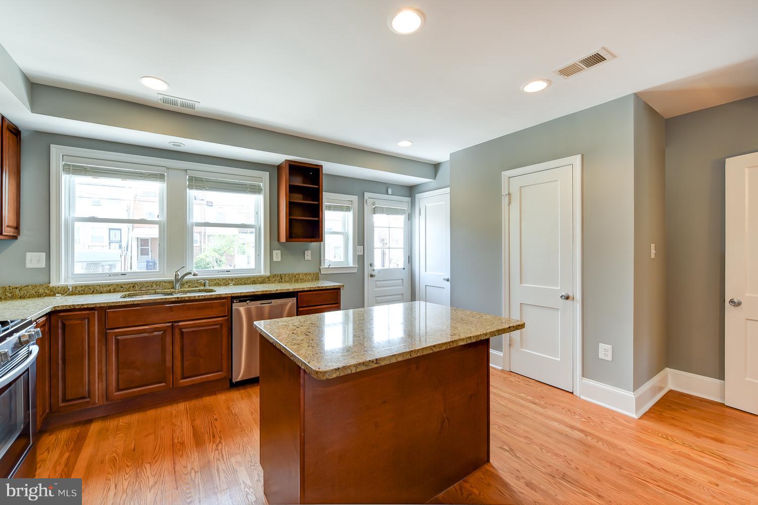 1334 Queen Street Northeast Washington, DC 20002 - Photo 9 of 29 a large kitchen with stainless steel appliances granite countertop a sink and dishwasher wooden cabinets with a large window