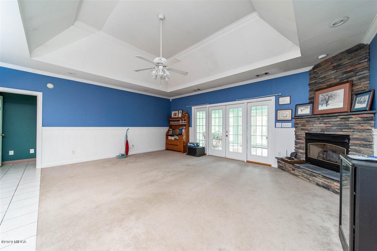 4271 Upper River Road Gray, GA 31032 - Photo 9 of 40 a view of a livingroom with a fireplace a ceiling fan and windows