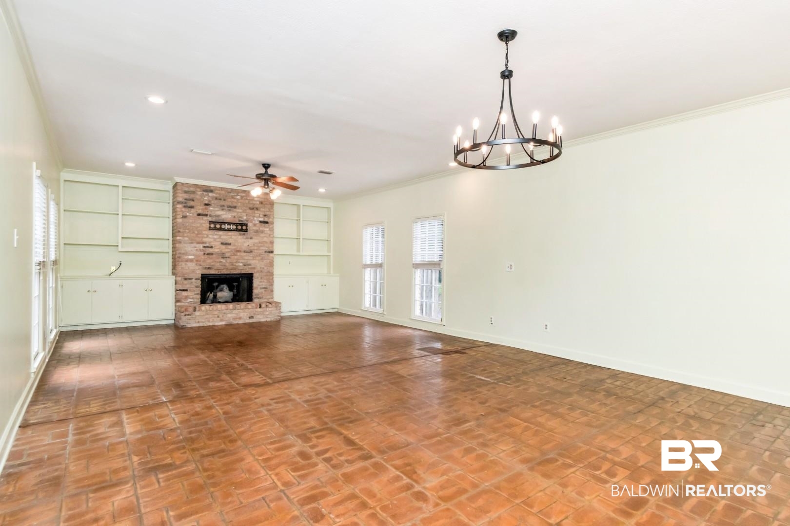 4776 Falls Church Road Mobile, AL 36608 - Photo 16 of 45 Spacious interior featuring brick-patterned flooring, a brick fireplace with hearth, and built-in shelving with lower cabinetry