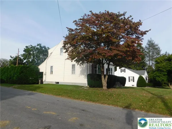 a view of a white house next to a yard and trees