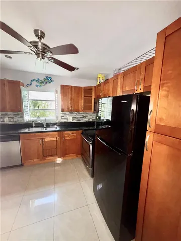 a large kitchen with granite countertop a refrigerator a stove a sink and dishwasher