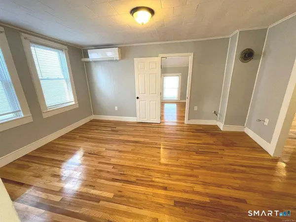 a view of empty room with wooden floor and fan