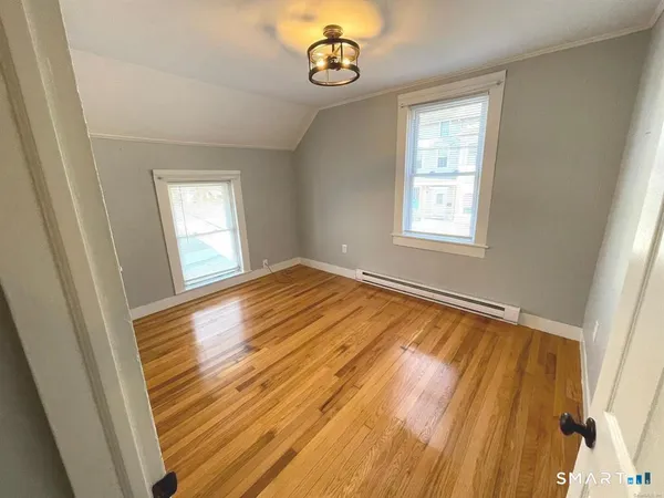 a view of an empty room with wooden floor and a window