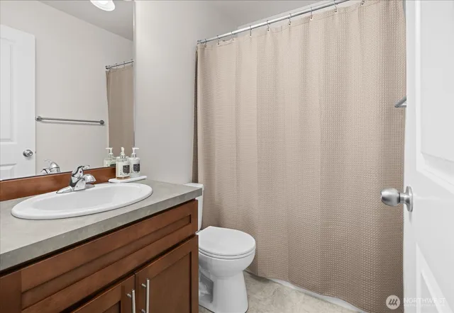 a bathroom with a sink a toilet and shower curtain