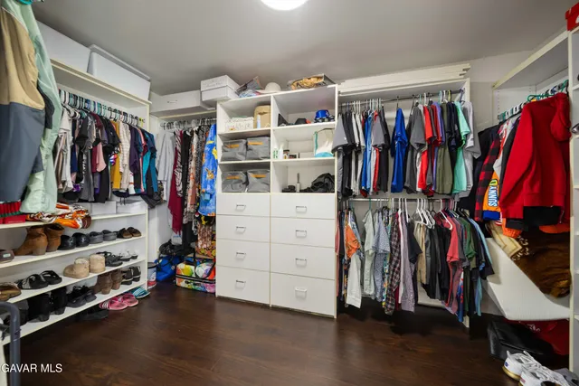 a view of walk in closet with clothes and shoes