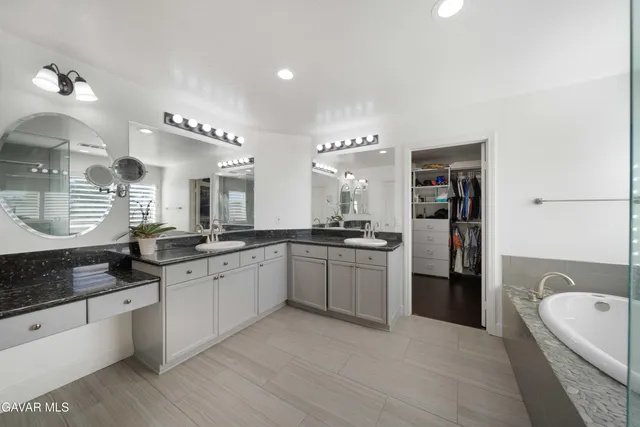 a large white kitchen with a large window a sink and stainless steel appliances