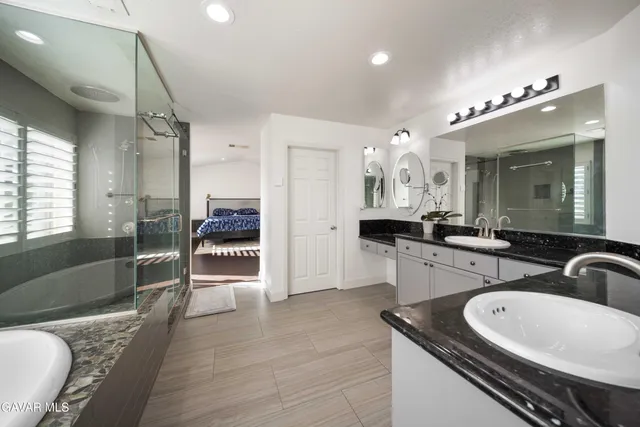 a bathroom with a granite countertop sink mirror and a bathtub
