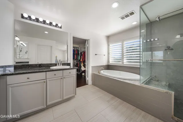 a spacious bathroom with a granite countertop tub a double vanity sink a vanity and a large mirror