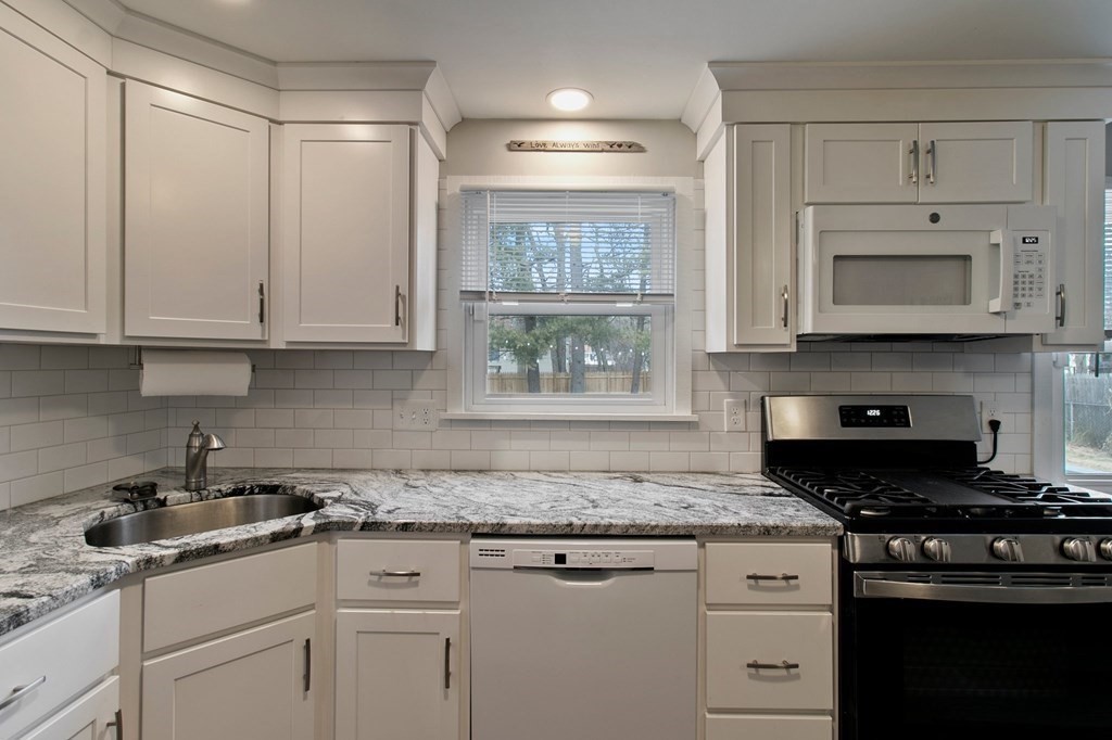 52 Portulaca Drive Springfield, MA 01129 - Photo 8 of 36 a kitchen with granite countertop white cabinets and black stainless steel appliances